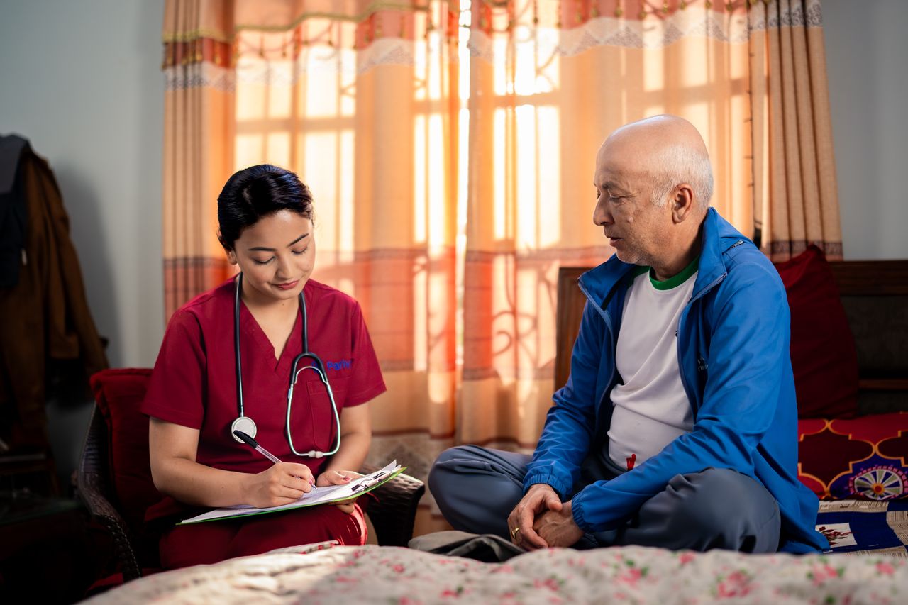 A Parivar nurse sharing a warm, cheerful moment with an elderly patient