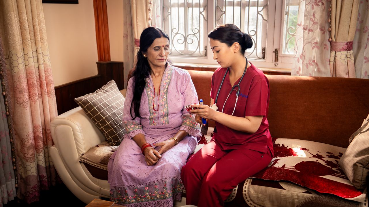 A Parivar nurse explaining medication to an elderly woman during a home visit in Nepal